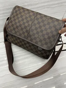 Vue détaillée du sac bandoulière à carreaux marron avec sangle réglable et rabat.