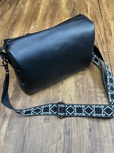 Sac bandoulière souple noir en cuir avec sangle à motif géométrique pour homme élégant.