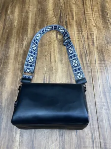 Vue détaillée d'un sac bandoulière noir en cuir pour homme avec sangle à motifs et métal.
