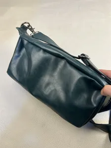 Detail close-up of dark green retro leather crossbody bag, showing fine texture and hardware.