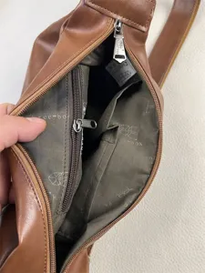 Detailed view of the brown sling bag interior, showing compartments, lining, and zipper quality.