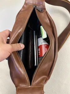 Detailed view of brown leather sling bag interior capacity showing daily essentials storage.