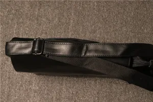 Men's shoulder bag detailed view showing black leather strap, metal buckle and smooth zipper.