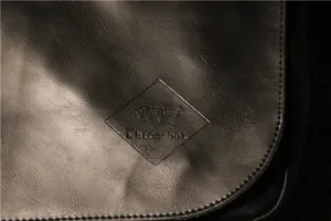 Close-up detail of vintage men's leather shoulder bag featuring debossed logo and texture.