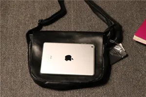 Detail view of black retro leather crossbody bag with adjustable strap and size reference iPad.