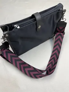 Black nylon crossbody bag detail, casual shoulder bag with wide pink chevron strap and metal hardware