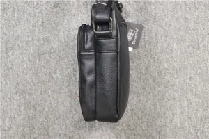 Side detail view of a black vertical leather shoulder bag showing zipper pocket and strap.