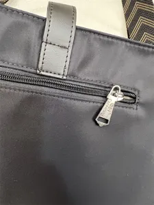 Close-up detail of threebox black nylon cross-body bag zipper and strap craftsmanship.