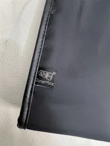 Detail shot of black nylon messenger bag edge with brand label and leather trim.