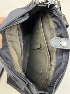 Interior detail view of black nylon crossbody bag, showing multi-compartment and zipper pocket.