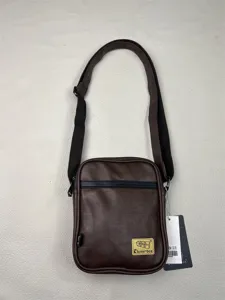 Detailed view of brown vertical messenger bag showing durable PU leather, zipper and strap.