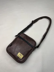Brown PU leather vertical crossbody bag detail, featuring adjustable strap and patch.