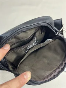 Interior detail view of the black crossbody bag showing multi-compartment storage and zipper pocket.