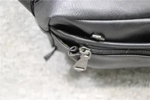 Detail shot of black faux leather men's crossbody bag zipper hardware and texture.