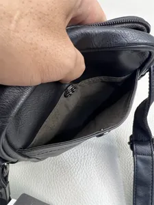 Detail view of black PU leather crossbody bag interior compartment and zipper pocket craftsmanship.