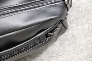 Black PU leather messenger bag detail showing smooth zipper pocket and fine stitching craftsmanship.