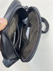 Black crossbody bag interior detail with multiple zipper compartments and spacious storage pockets.