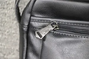 Black soft leather crossbody bag detail view showing the metal zipper pull and texture.