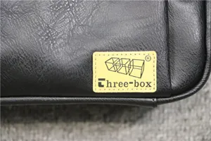 Detailed view of black faux leather crossbody bag showing brand logo label and texture