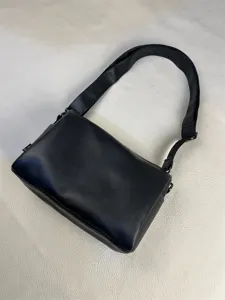 Detail shot of a minimalist black shoulder bag, sleek design for daily commute and casual wear.
