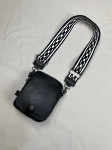 Black vertical crossbody bag for men with stylish wide black and white woven strap.