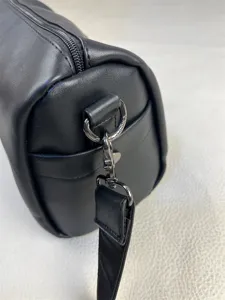 Black cylindrical shoulder bag with smooth zipper closure and metal hardware detail.
