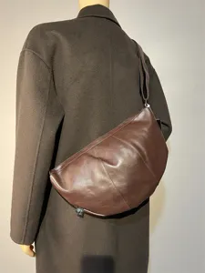 Detail view of brown leather cross-body dumpling bag, retro crescent style for commute.