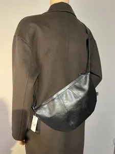 Black leather crescent crossbody bag for daily commute, minimalist stylish dumpling shoulder bag.