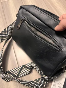 Close-up detail view of a black PU leather messenger bag featuring a patterned strap.