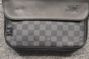 Nahaufnahme der grauen und schwarzen karierten Herrentasche, Detailansicht der Lasche.