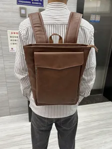 Brown leather backpack back view detail, featuring front flap pocket and sturdy shoulder straps.