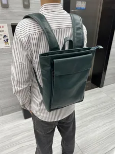 Detail view of dark green leather backpack worn on back, showing straps and pockets clearly.