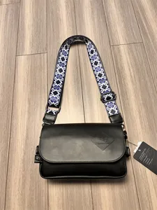 Detailed view of black messenger bag with blue patterned wide strap and embossed brand logo.
