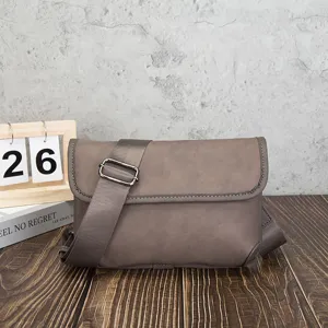 Close-up detail of the grey retro messenger bag highlighting soft texture and wide strap.