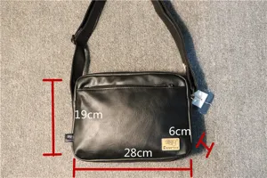 Close-up detail of a black casual shoulder bag with front zipper pocket and adjustable strap.