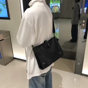 Vista detallada de un bolso bandolera de nailon negro, estilo cruzado casual para uso diario.