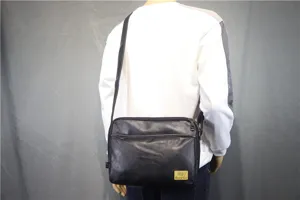 Detailed back view of a black PU leather messenger bag worn crossbody, showing casual style.
