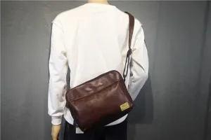 Detail view of the brown leather crossbody shoulder bag showing texture and strap buckle.