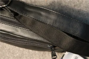 Men's black shoulder bag detail close-up, durable leather material, sturdy strap and metal zipper.