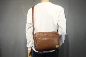 Brown leather messenger bag detail view, casual cross-body style with front pocket and zipper.