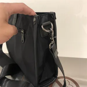 Primer plano detalle del bolso bandolera de nailon negro para hombre, herrajes.