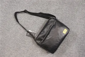 detail view of black leather messenger bag, minimalist horizontal shoulder bag for men.