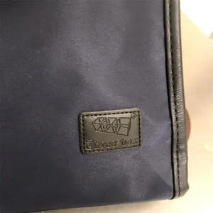 Primer plano detallado de la bolsa mensajero de nailon duradero con parche de logo y costuras.