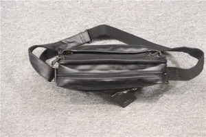 Detailed view of the black leather cross-body bag showing multiple zipper compartments.