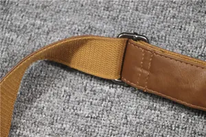 Close-up detail of adjustable brown canvas and leather cross-body bag strap with metal buckle.