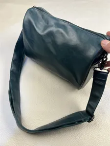 Dark green cylindrical shoulder bag, casual crossbody bag with adjustable wide strap for daily commute.