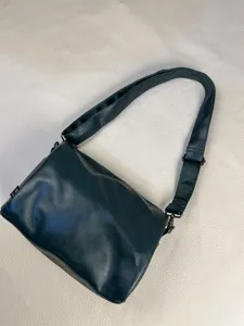 Detailed view of dark green minimalist shoulder bag with adjustable strap for daily commute.