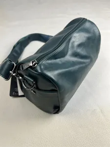 Dark green cylindrical shoulder bag detail, premium leather daily commuter crossbody bag.