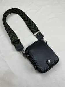 Detailed view of men's black vertical crossbody bag with wide patterned strap and silver hardware.