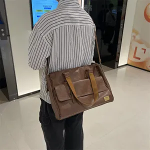 Sac bandoulière en cuir PU marron porté sur modèle, montrant la sangle et la poche avant.